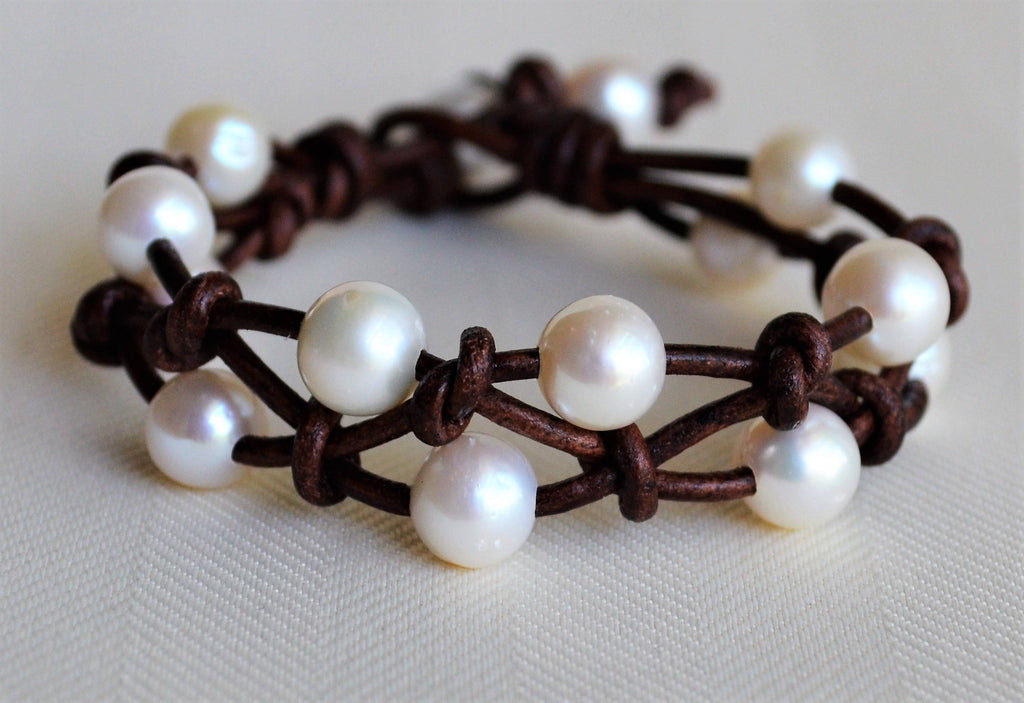 Bracelet with white pearls and brown leather straps on a light background