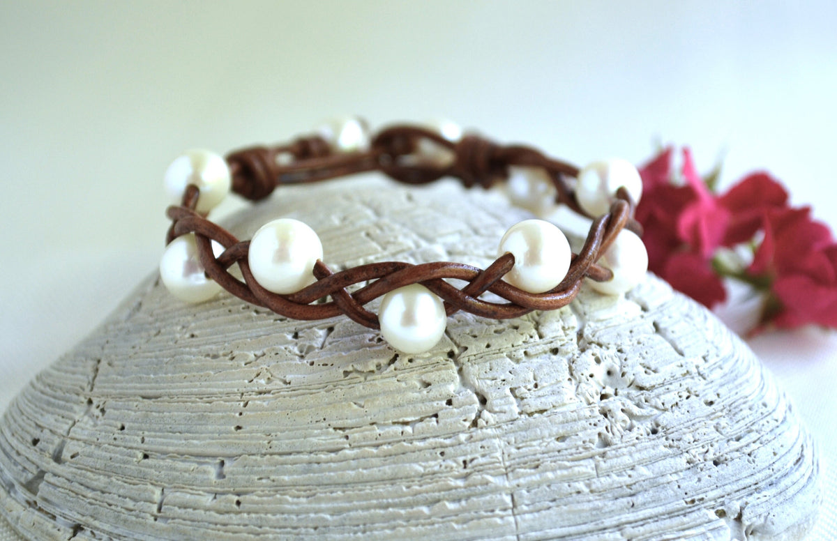 Bracelet with pearls on a textured surface with flowers in the background