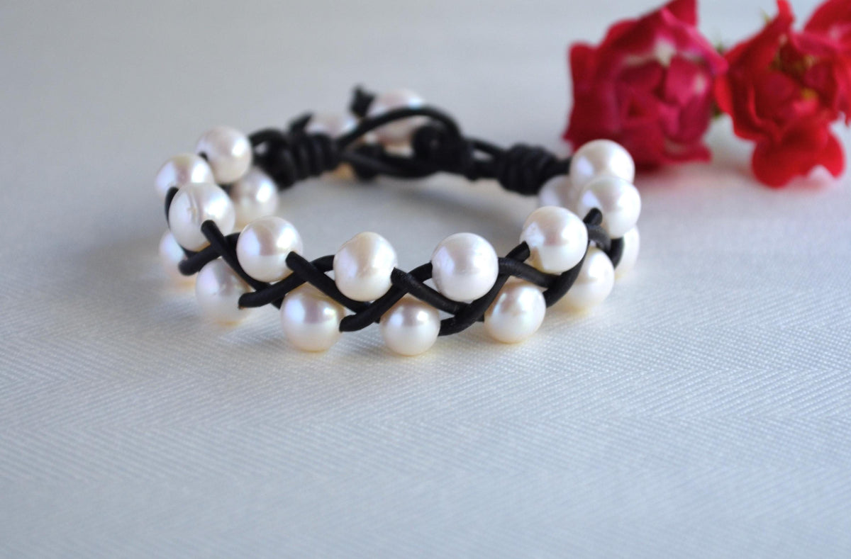 Pearl bracelet on a white background with red flowers in the corner