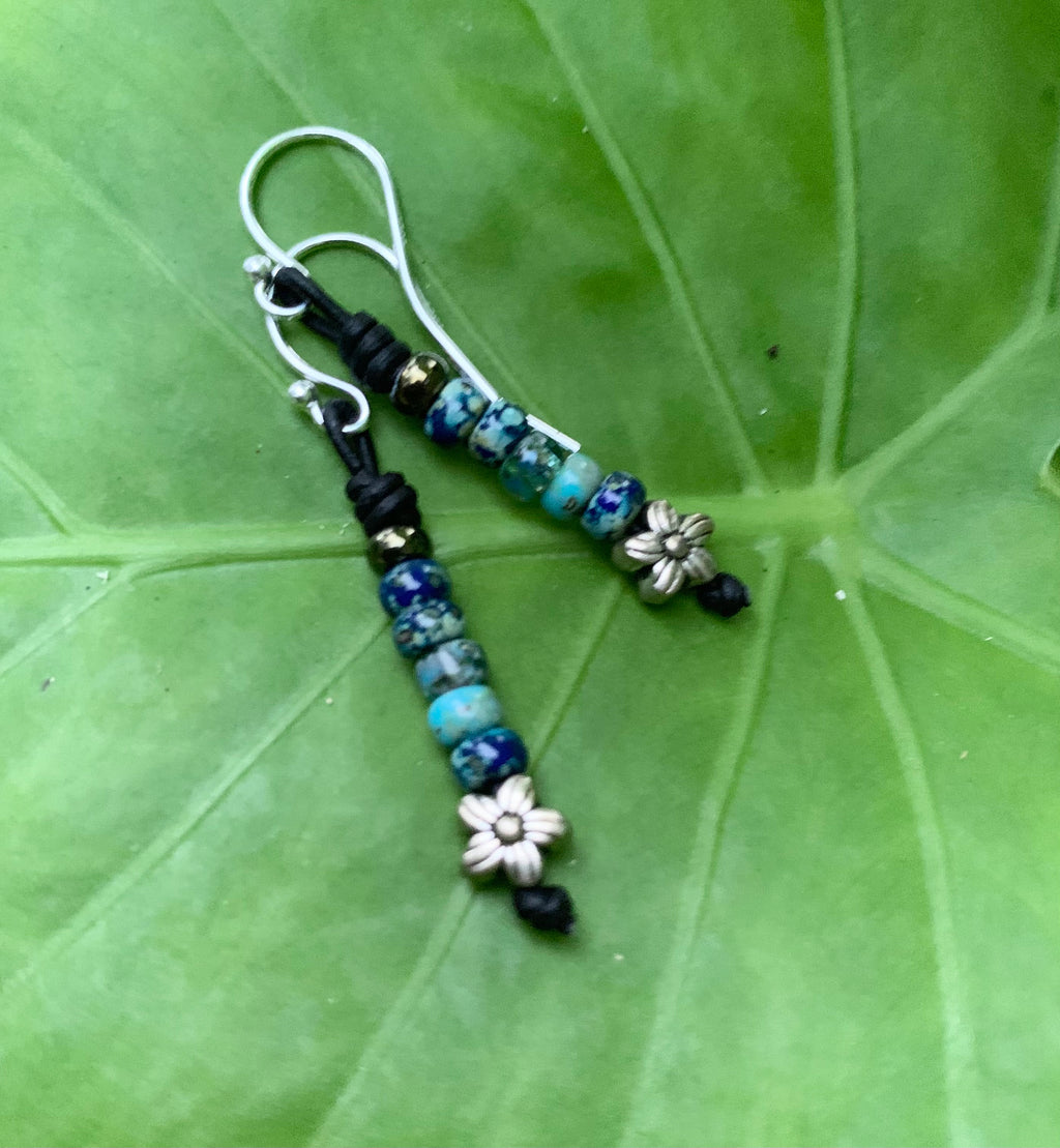 Beaded earrings with floral designs on a green leaf background