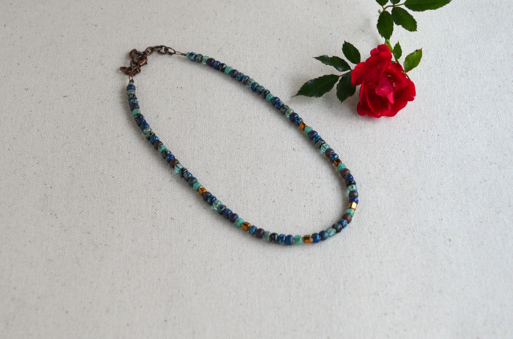 Beaded necklace on a light gray background with a red rose.
