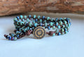 Multistrand beaded bracelet with a central button-like charm on a light background