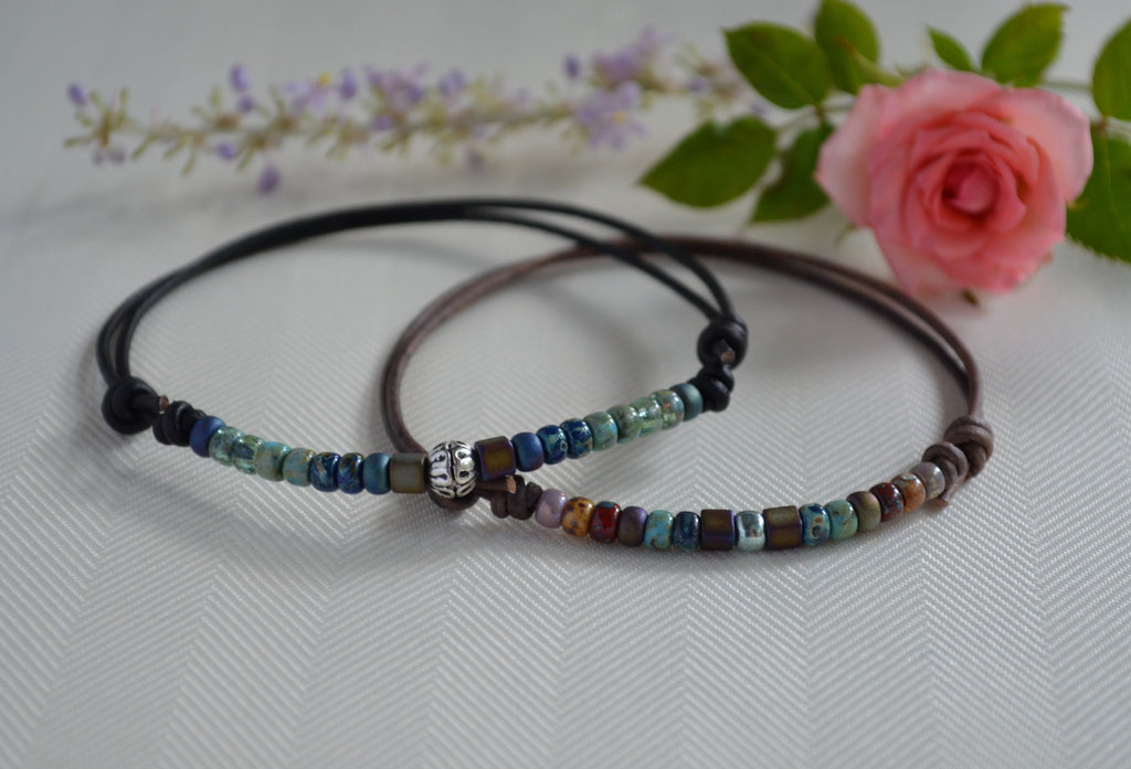 Beaded ankle bracelet on a white surface with flowers in the background