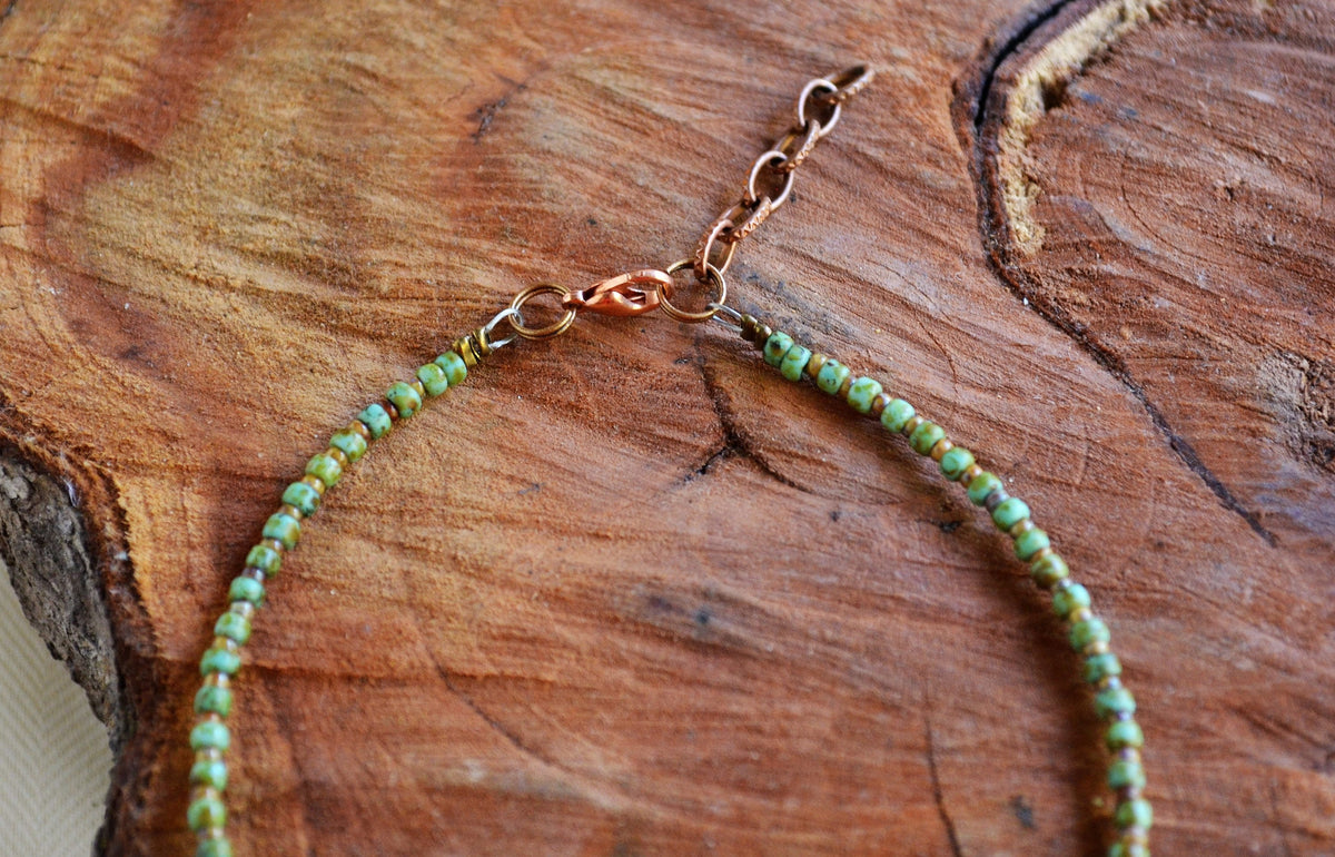 Anklet with green beads and gold chain on a wooden surface
