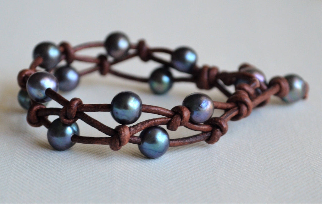 Bracelet with brown leather strap and peacock freshwater pearls on a light background