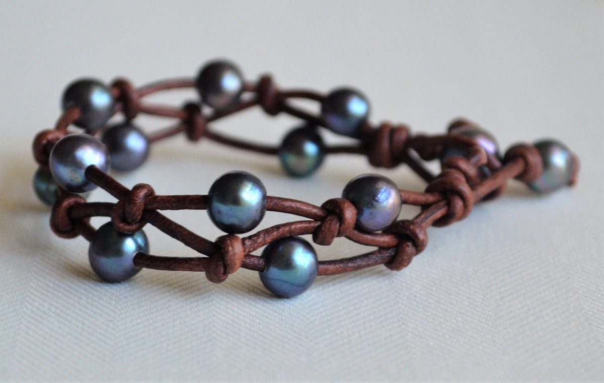 Bracelet with brown leather strap and peacock freshwater pearls on a light background