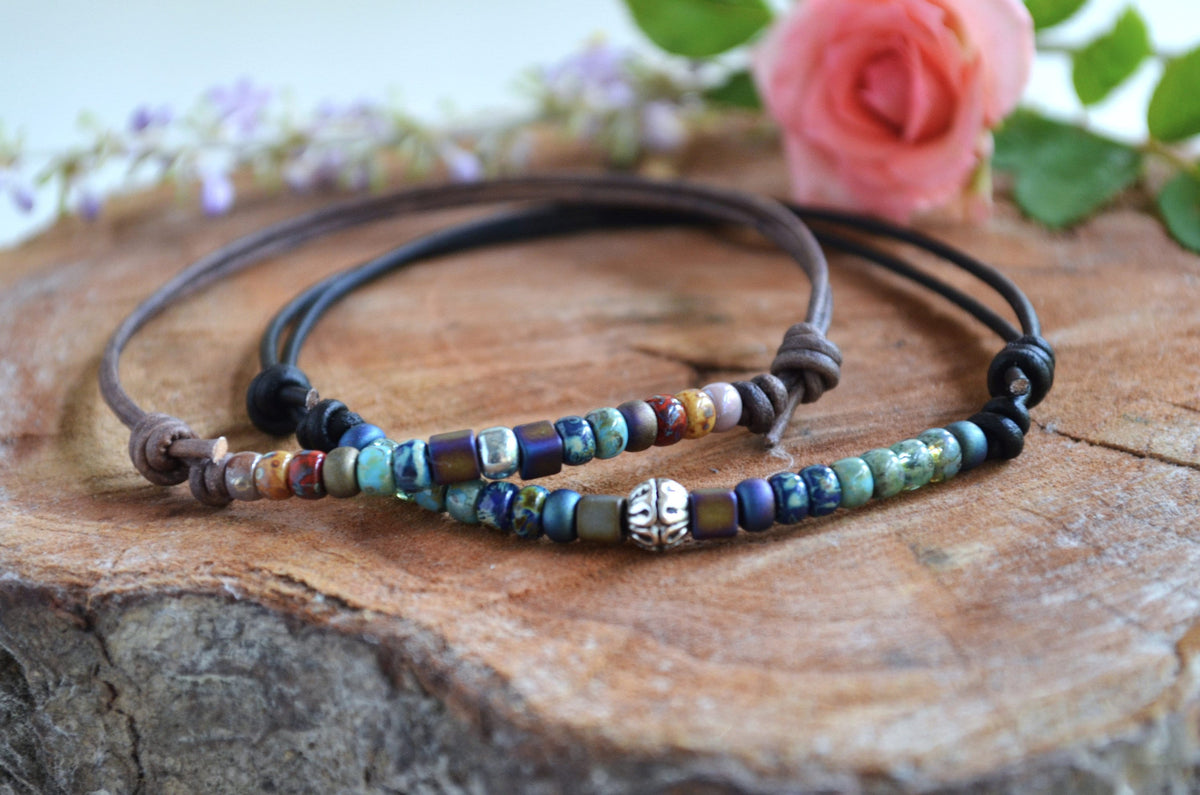 Beaded anklet on a wooden surface with flowers in the background