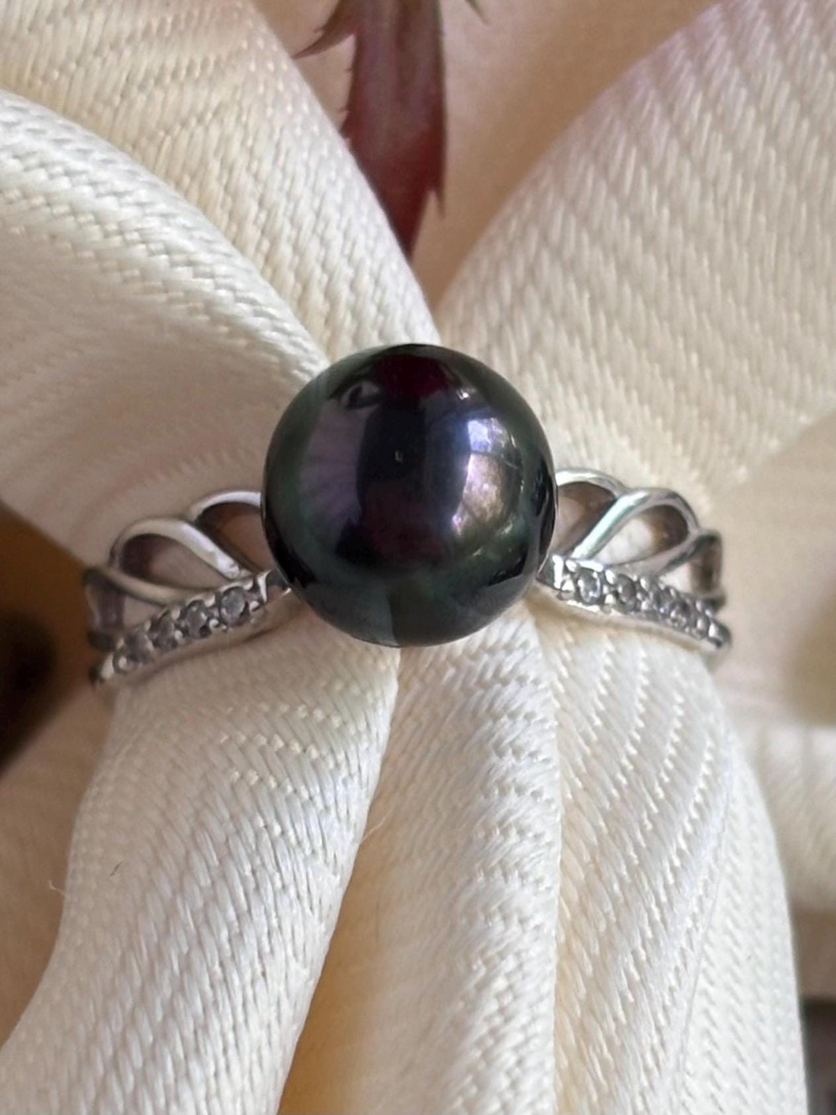 Ring with a black pearl on a white fabric background