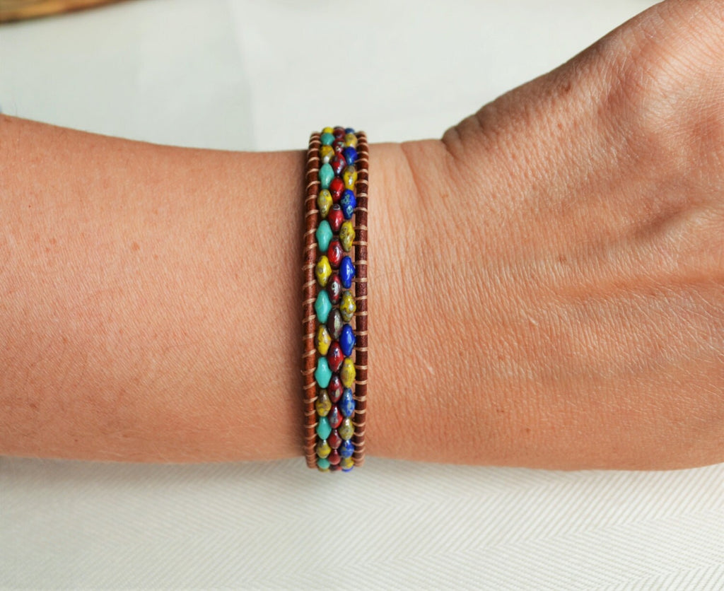 Multicolored beaded bracelet on a wrist against a white background