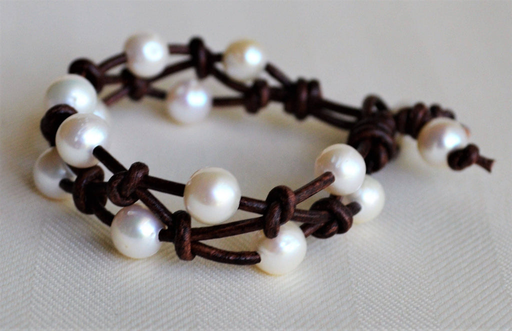 Bracelet with white pearls and brown leather straps on a light background