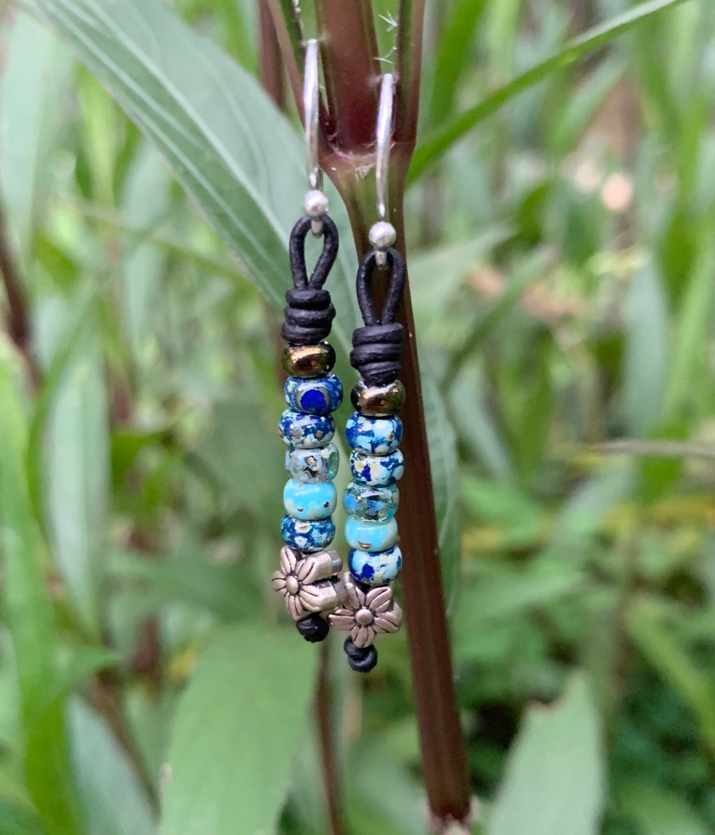 Beaded earrings hanging from a plant with a natural green background