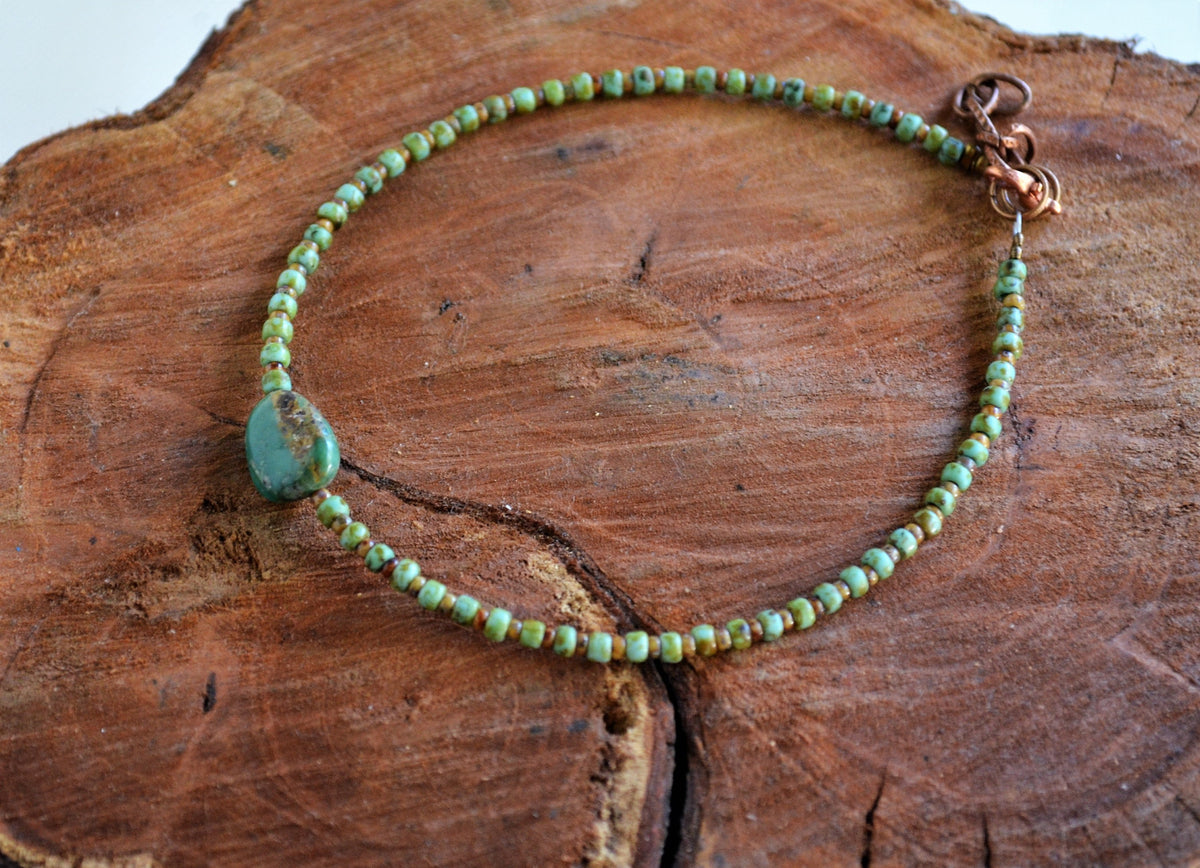 Green beaded anklet on a wooden surface