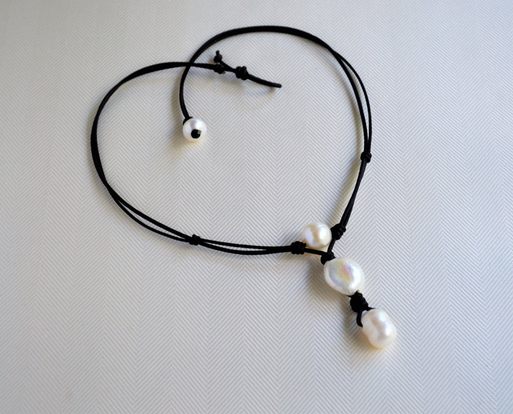 Black cord necklace with white pearls on a light gray background