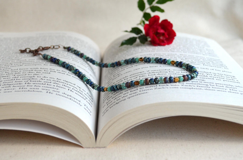 Colorful beaded necklace on an open book with a red flower