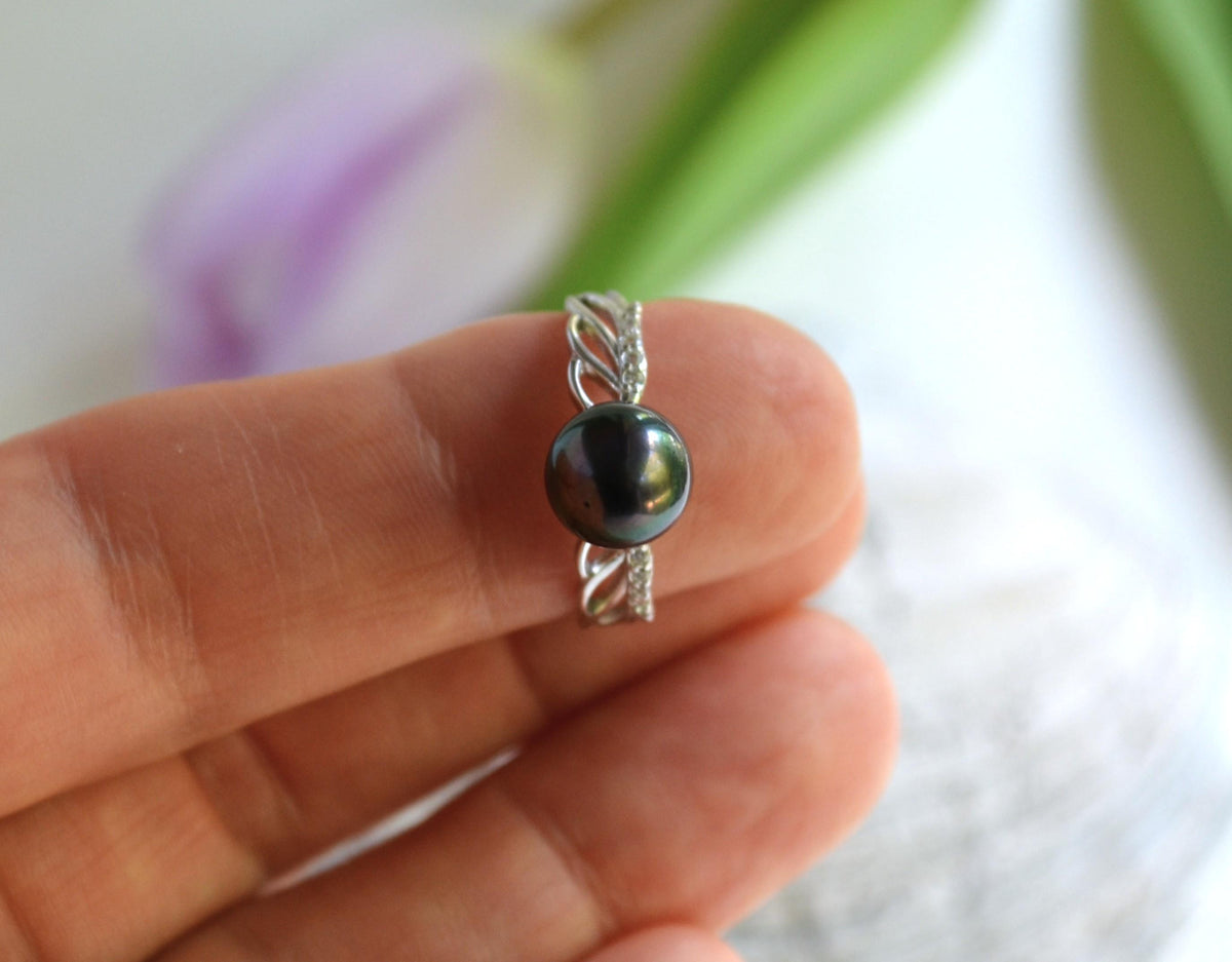 Silver ring with Tahitian pearl held on a hand against a blurred background