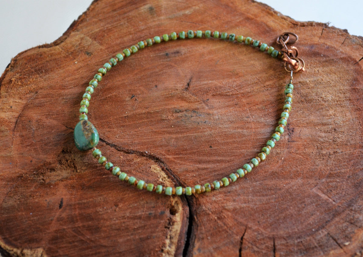Green beaded anklet on a wooden surface