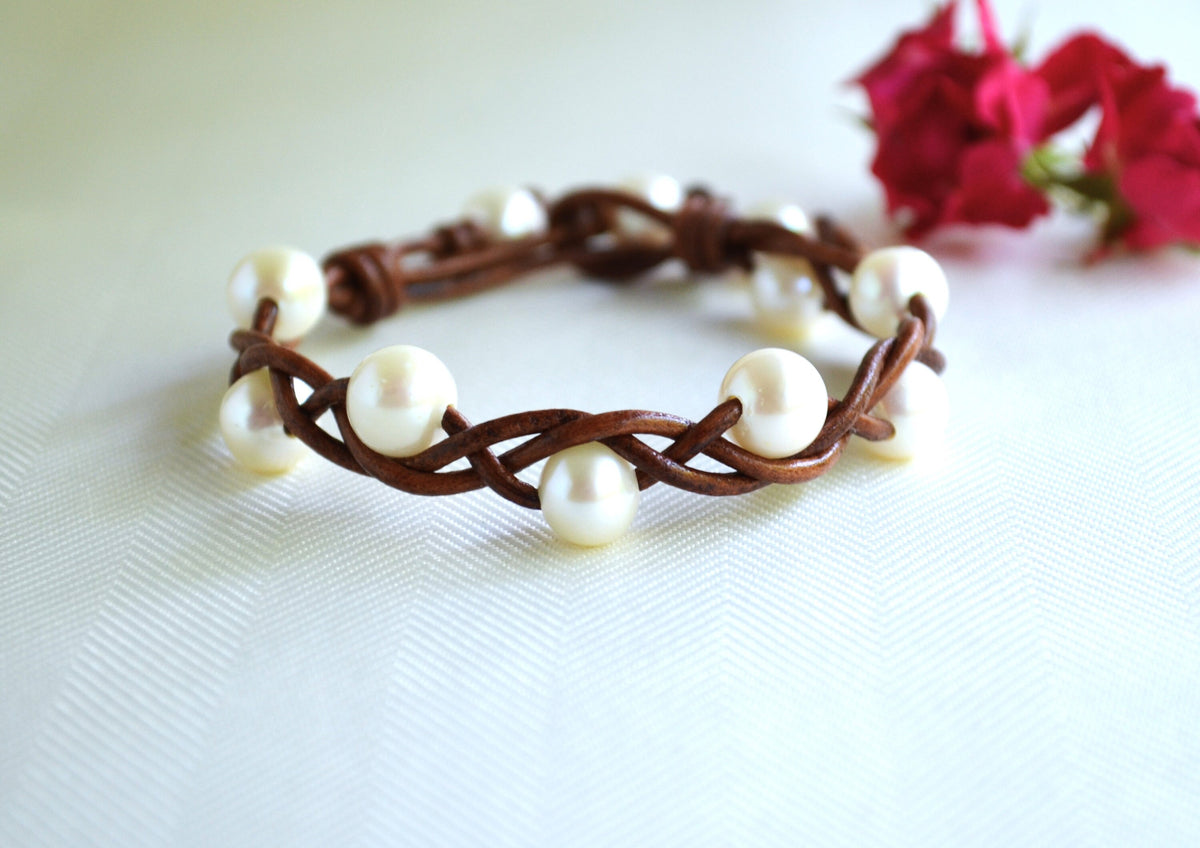 Bracelet with white pearls and brown woven band on a light background
