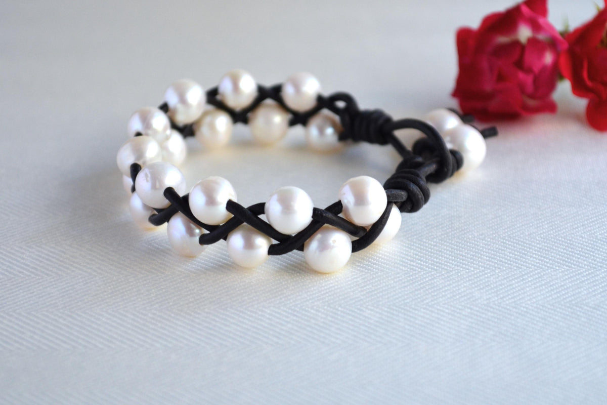 Pearl bracelet with black cord on a light gray background