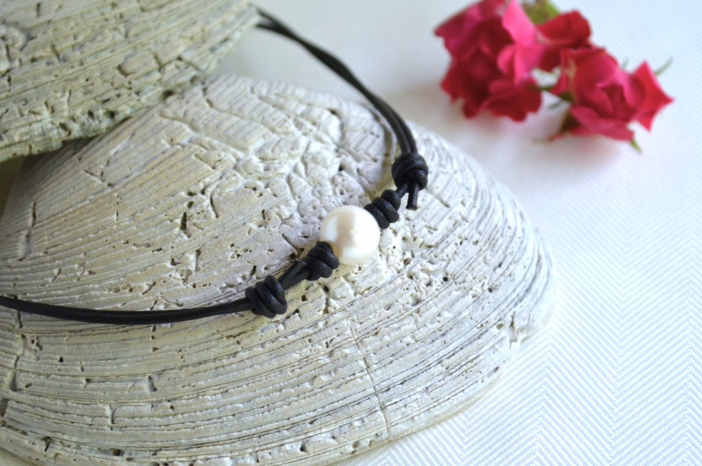Choker with a pearl on a textured surface with flowers in the background