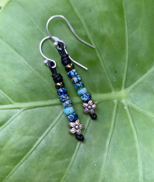 Pair of beaded earrings on a green leaf