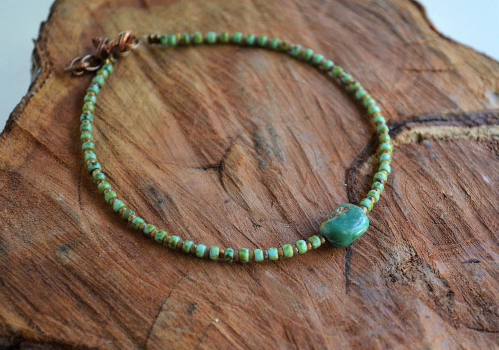 Green beaded anklet on a wooden surface