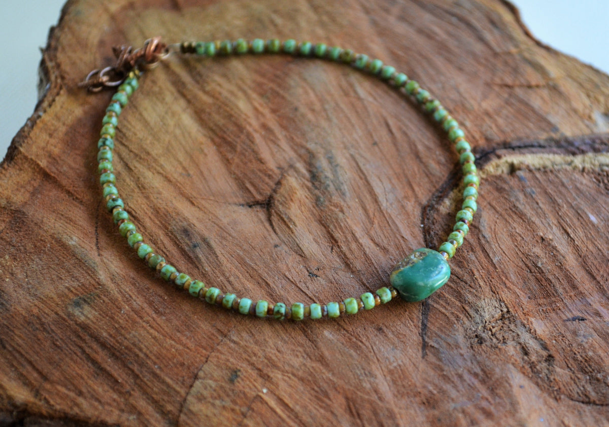 Green beaded anklet on a wooden surface