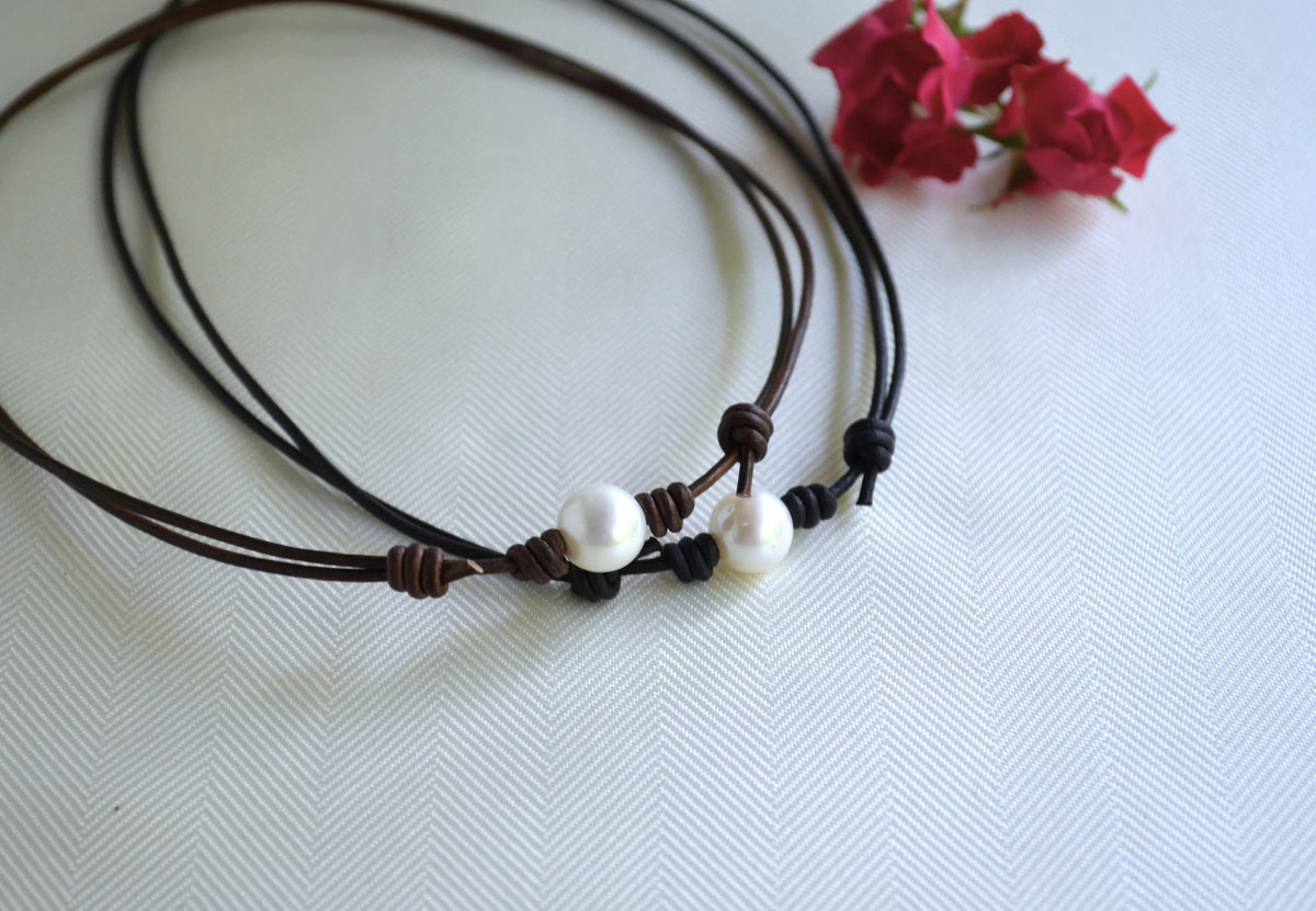 Two brown cord necklaces with white beads on a light background
