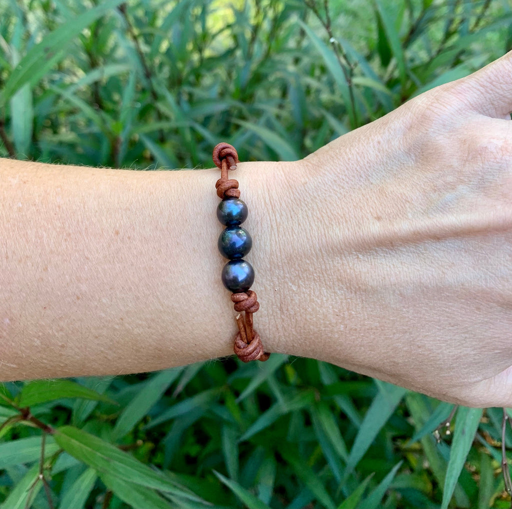 Bracelet with blue pearls beads on a wrist against a green leafy background