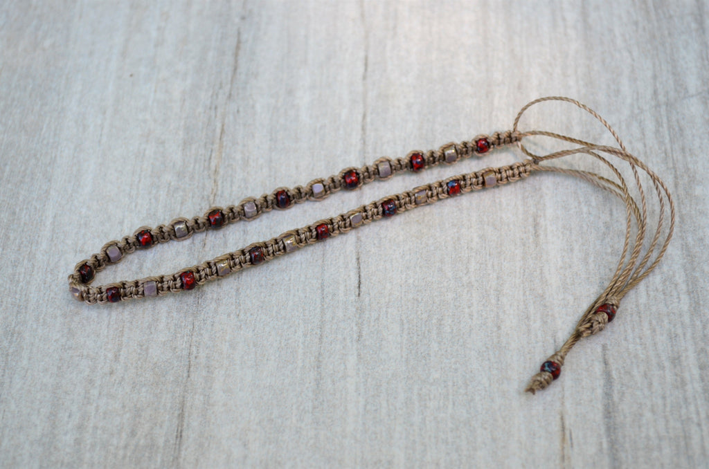 Beaded string with maroon and beige beads on a light wooden surface