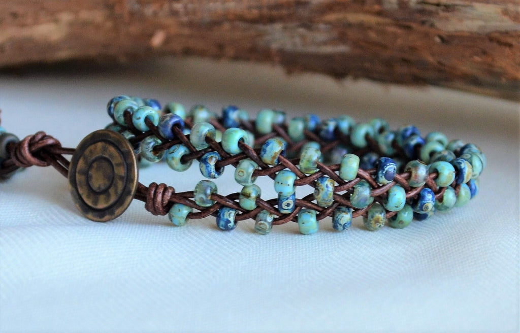 Beaded bracelet with blue and green beads and a copper clasp on a white surface.