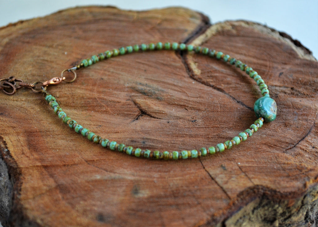 Green beaded anklet on a wooden surface