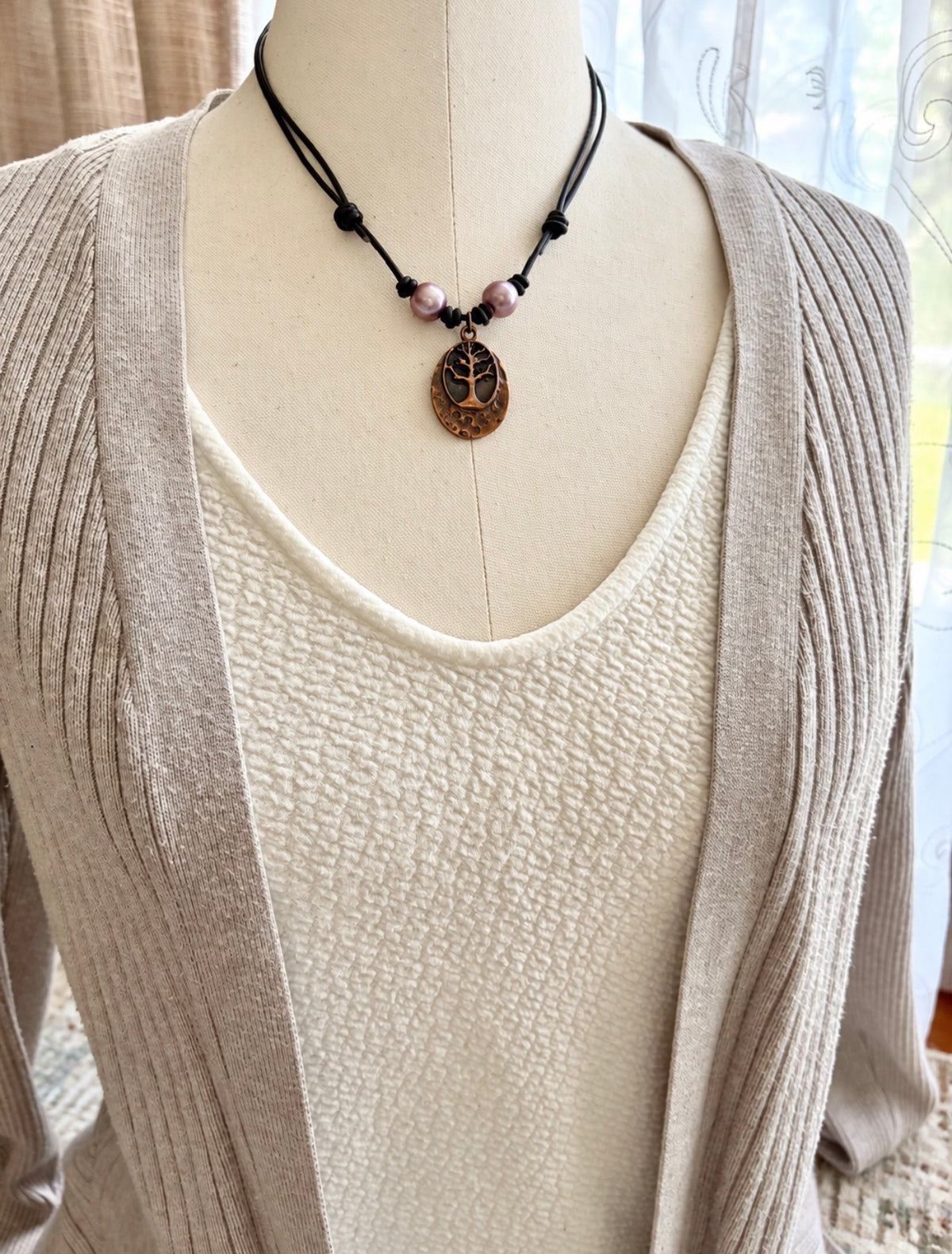 mannequin showcasing pink pearls on leather necklace with tree of life pendant