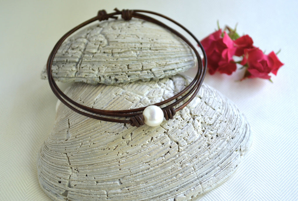 Choker necklace on a textured surface with pink flowers in the background