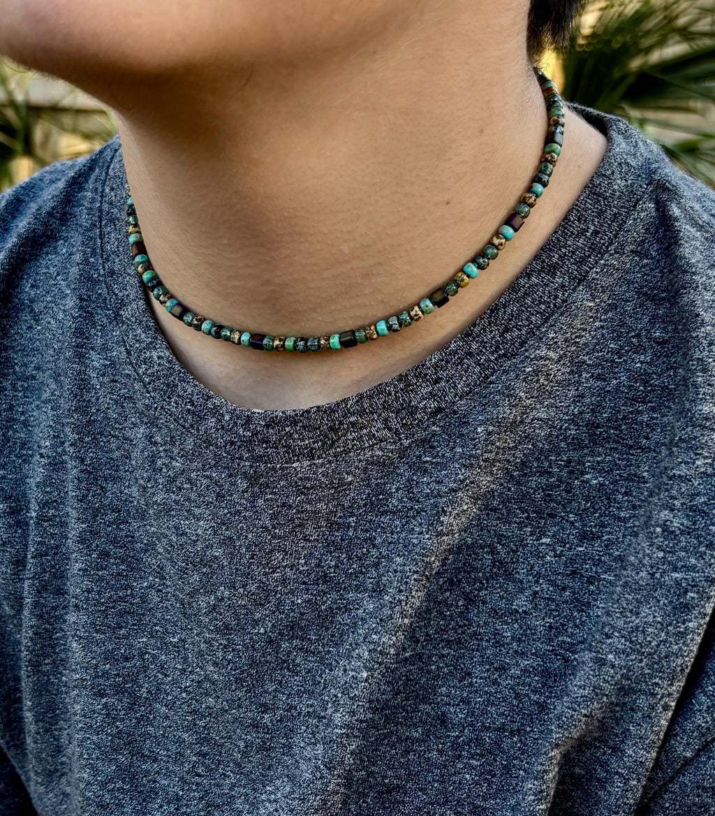 Person wearing a beaded necklace with a blurred background