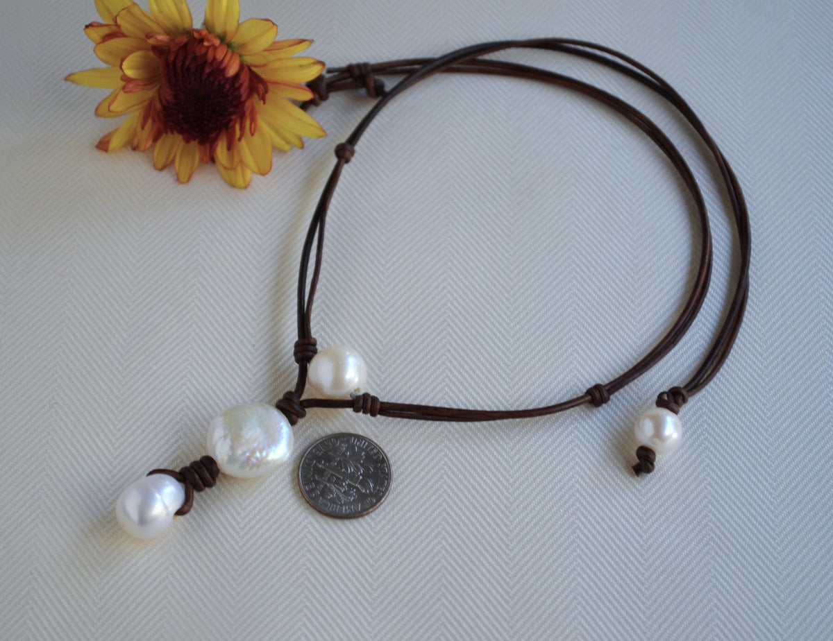 Necklace with pearls and a coin on a textured surface with a sunflower in the corner.