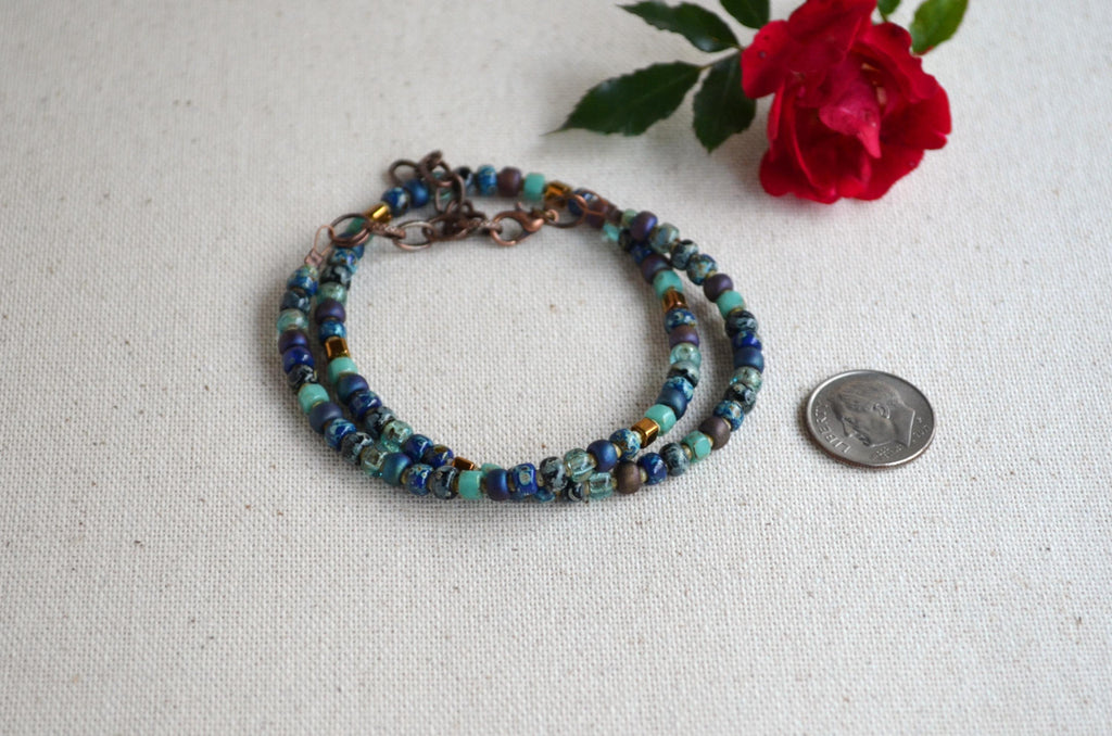 Multicolored beaded necklace on a light fabric background with a red rose.