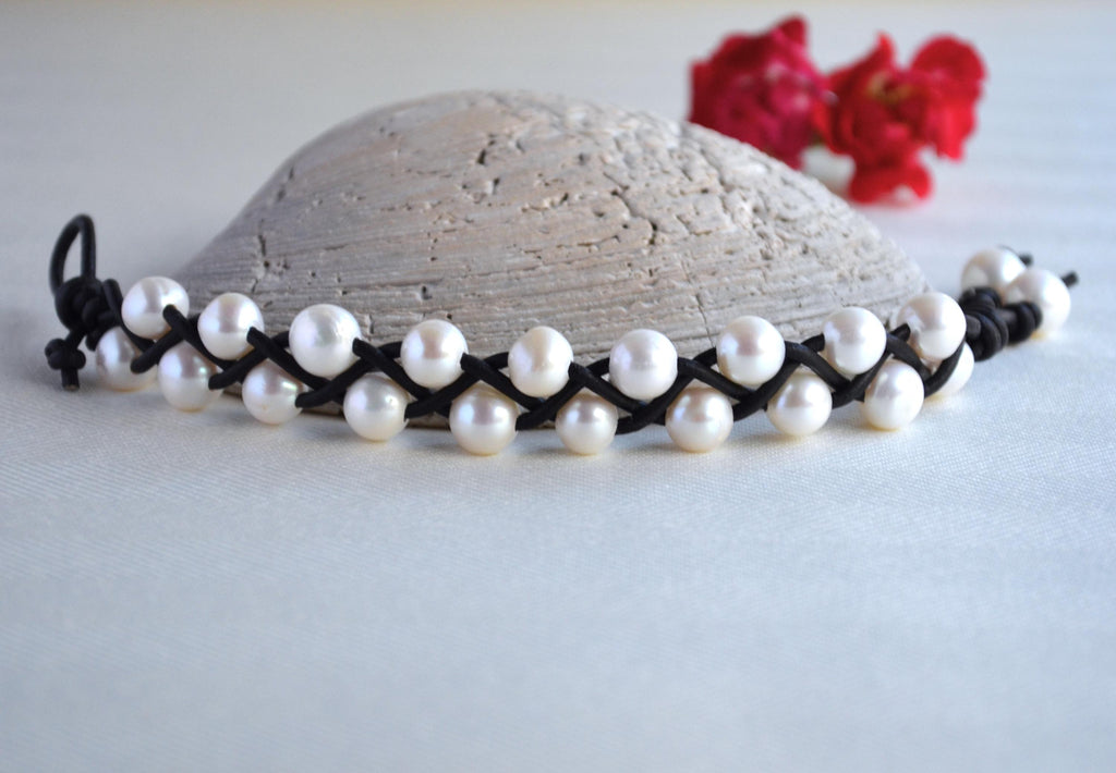 Pearl necklace on a stone surface with flowers in the background