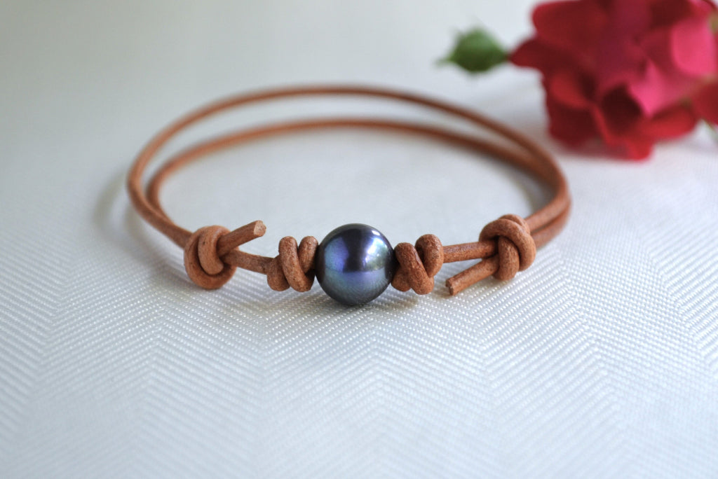 Brown leather bracelet with a blue bead on a white background