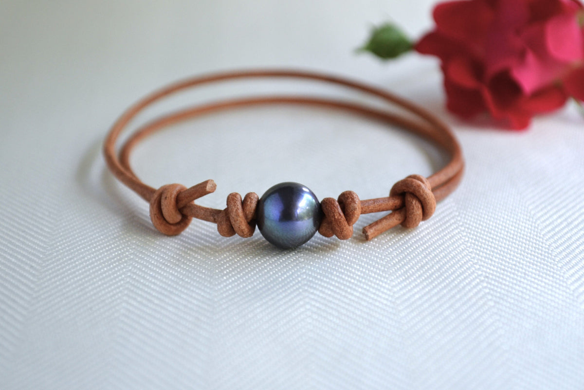 Brown leather bracelet with a blue bead on a white background