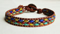 Multicolored beaded bracelet with brown leather wrap on a white background