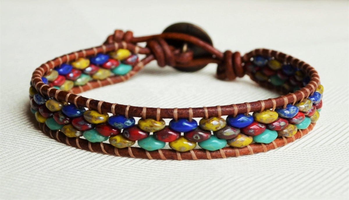 Multicolored beaded bracelet with brown leather wrap on a white background