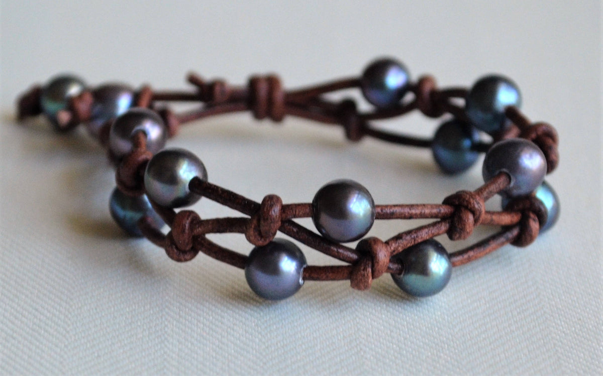 Bracelet with peacock freshwater pearls and brown leather straps on a light background