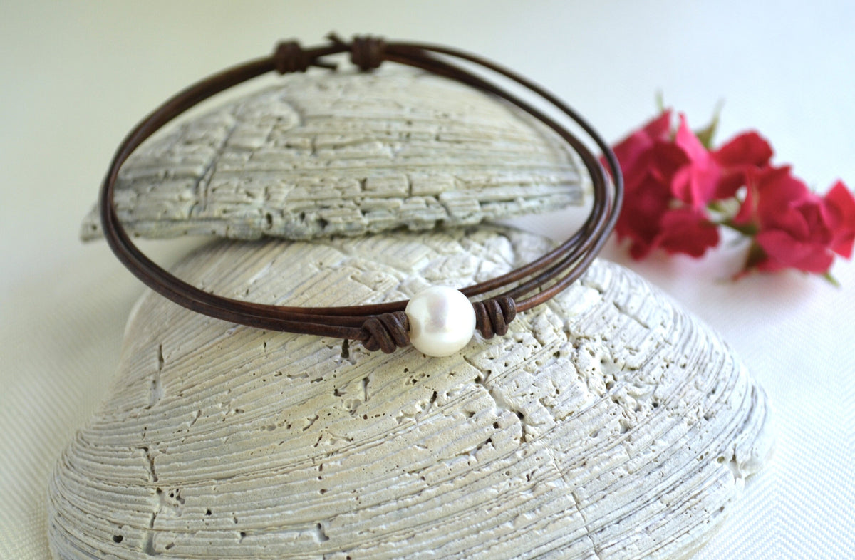 Choker with a pearl on a textured surface with flowers in the background