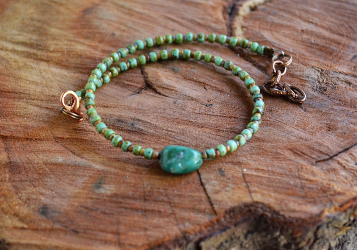 Green beaded ankle bracelet on a wooden surface