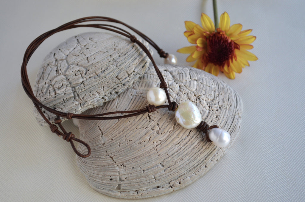 Bracelet with pearls on a stone surface with a yellow flower in the background