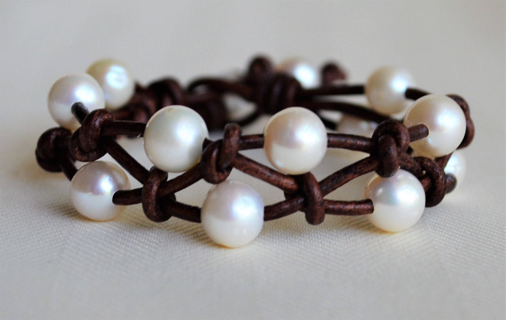 Bracelet with white pearls on a brown leather band on a light background