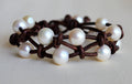 Bracelet with white pearls on a brown leather band on a light background