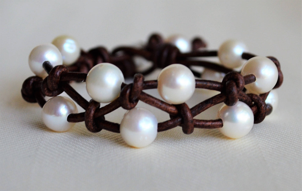 Bracelet with white pearls on a brown leather band on a light background