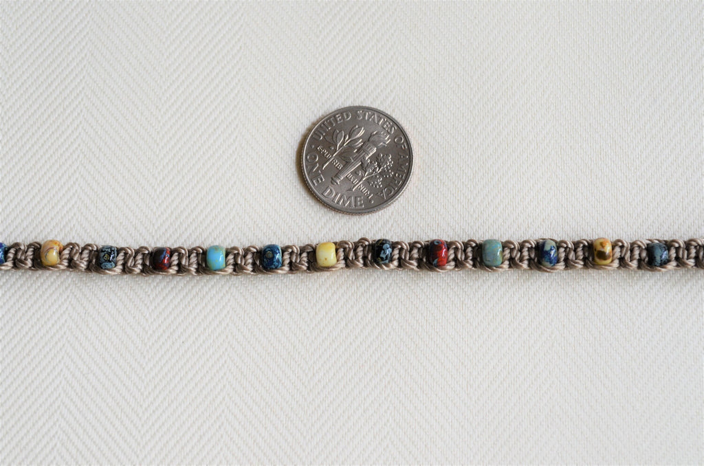 Beaded bracelet with multicolor beads next to a quarter on a white background